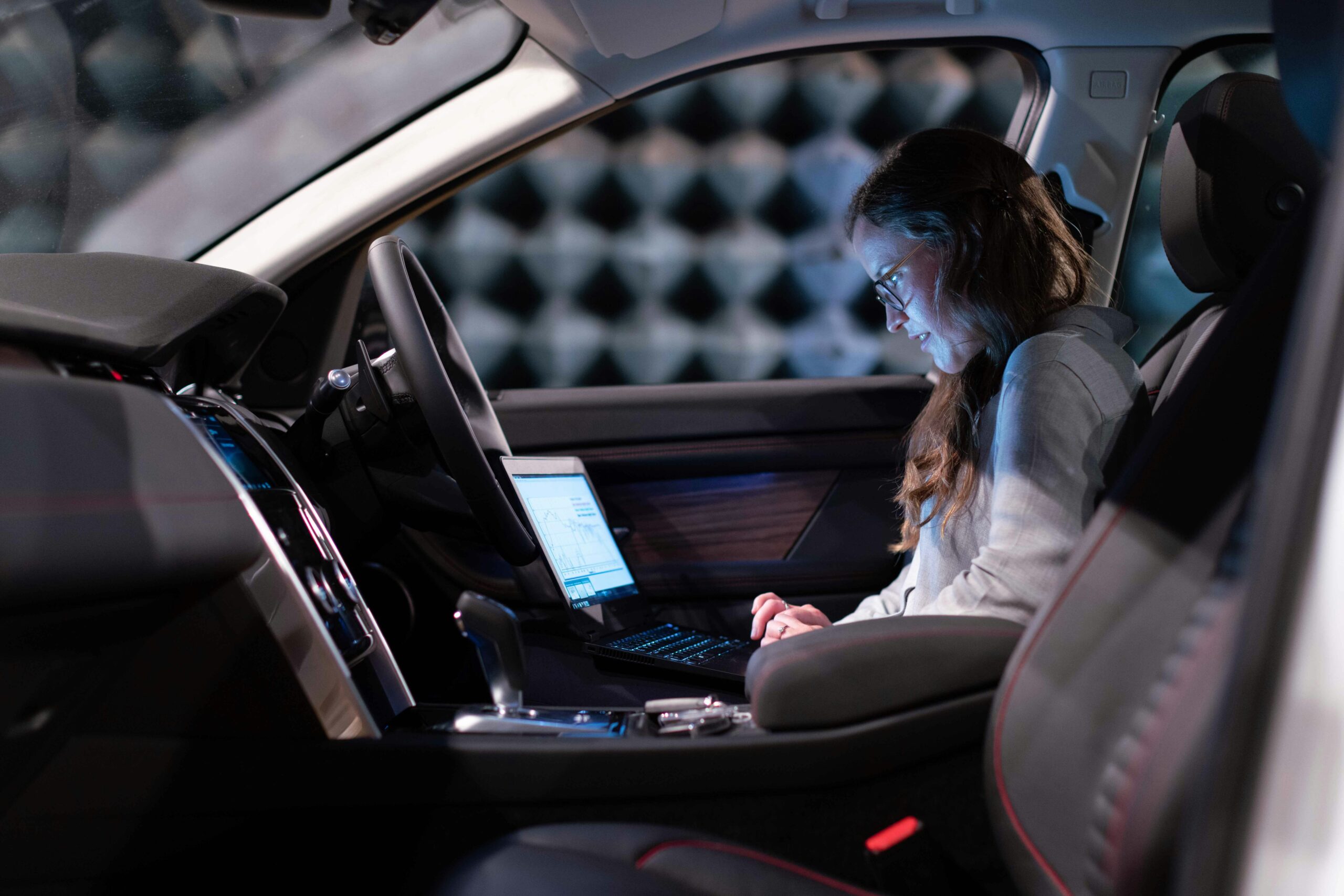 Woman using laptop in drivers seat